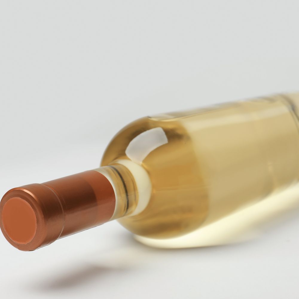 Study: a white wine bottle with a copper capsule, on a pale ground